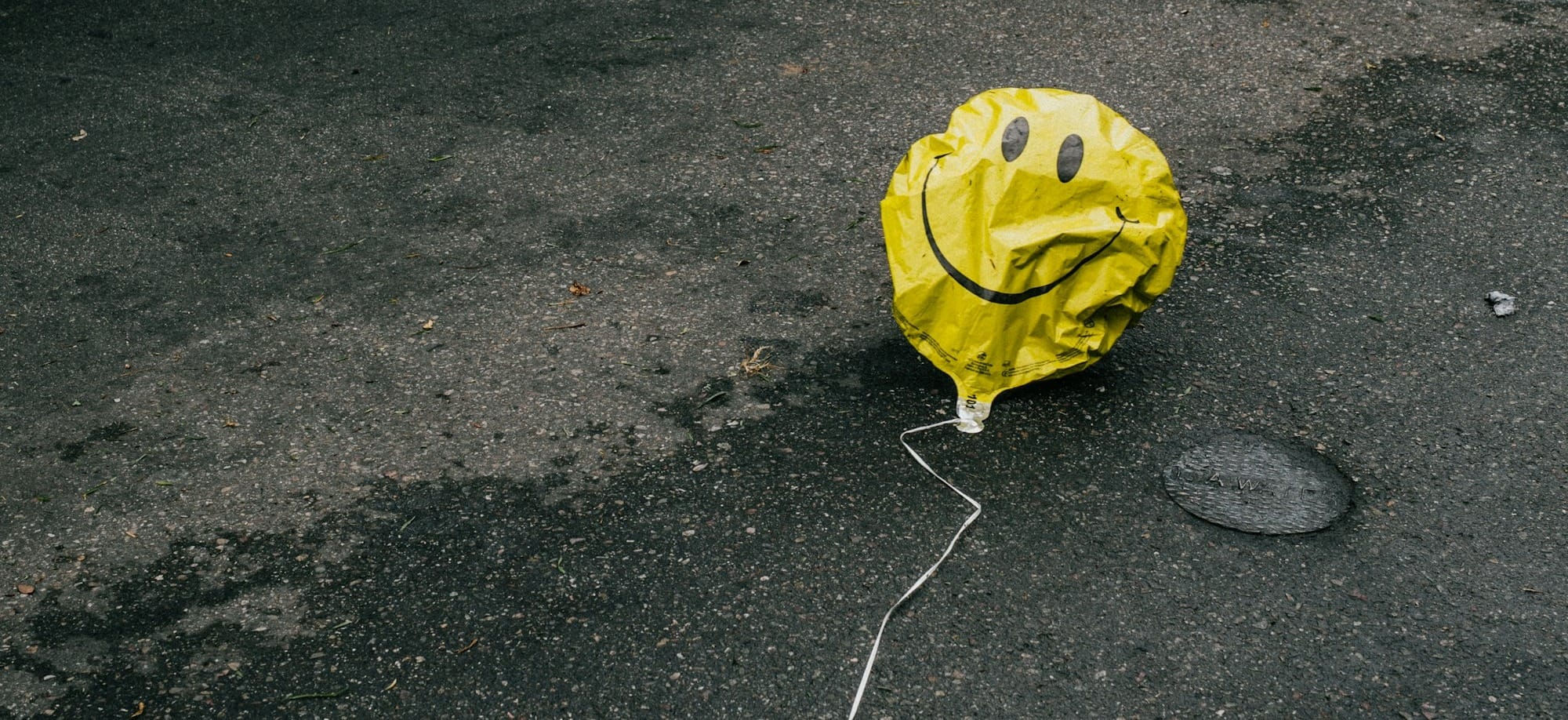 smiling emoji balloon beside black car during daytime