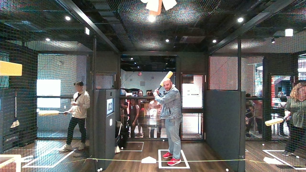 The author stands in a batting cage, waiting for his turn to hit.